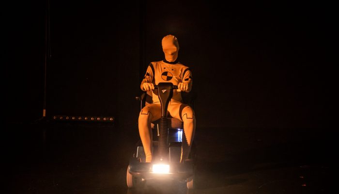 Stadttheater Ein Crash-Text-Dummy fährt auf einem Elektromobil über die Bühne.