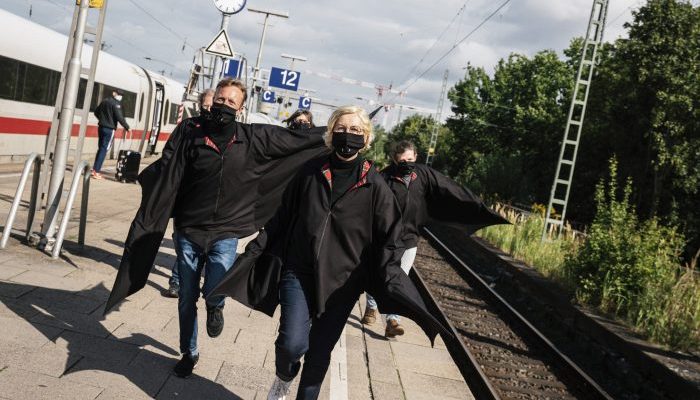 Rübermachen Ein Dutzend Menschen im Fledermauskostüm läuft auf einem Bahnsteig auf die Kamera zu.