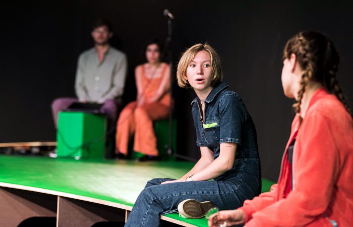 citizenpark_6 Zwei junge, weiblich gelesene Personen unterhalten sich. Im Hintergrund sitzen zwei weitere Personen und hören zu.