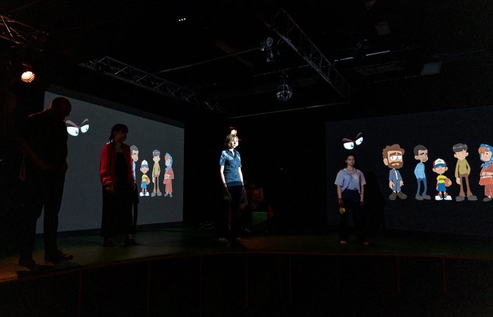 Citizenpark_3 Vier junge Menschen im Dunklen vor zwei Leinwänden mit Comiczeichnungen.