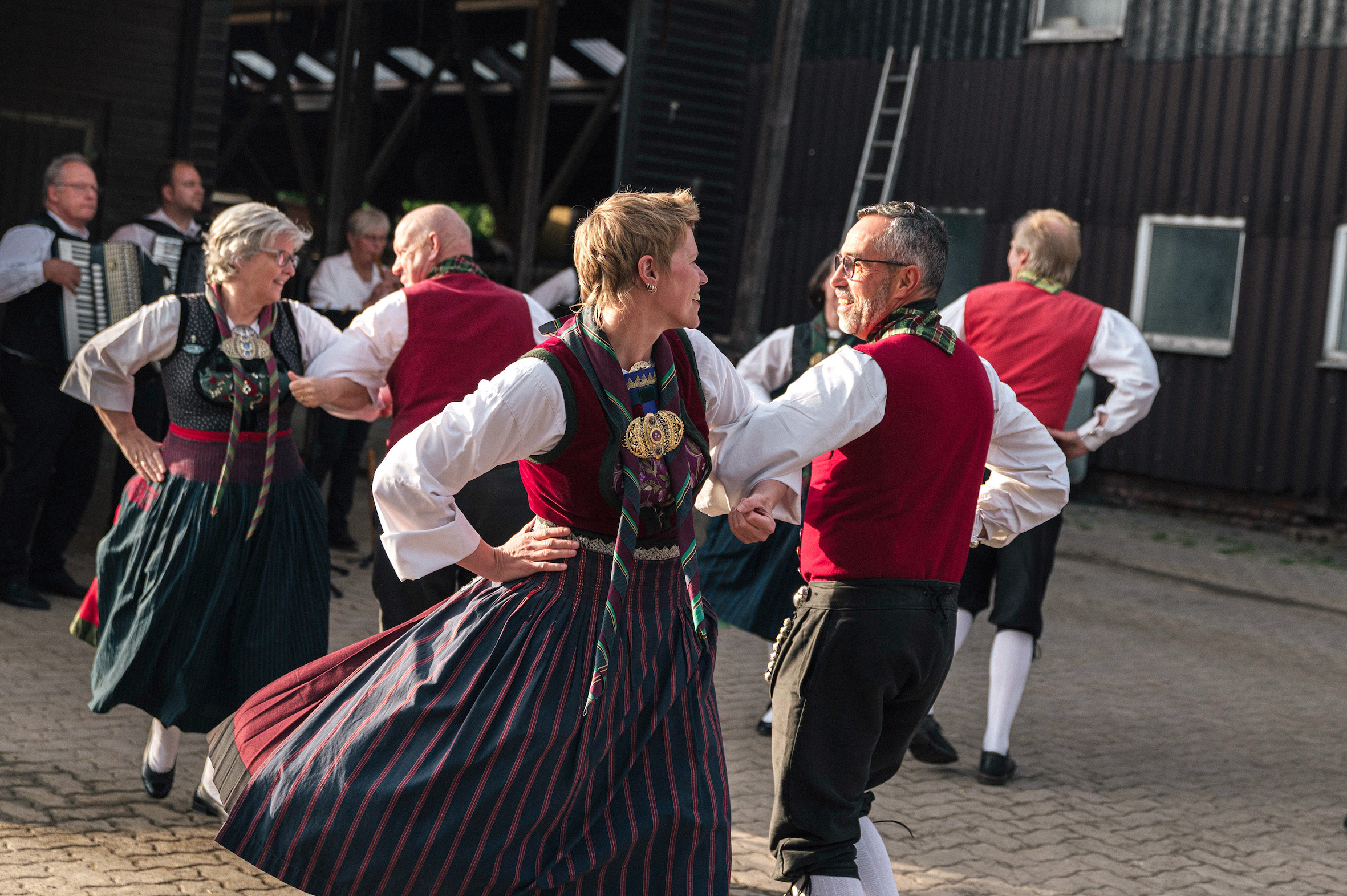 Eine Trachtengruppe tanzt vor einem Kuhstall