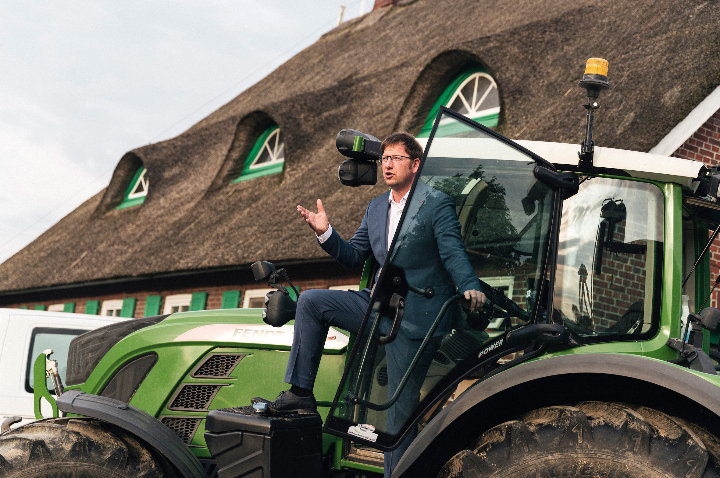 Ein Mann im Anzug steht auf einem Traktor und hält eine Rede