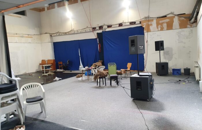 7c4fe1e2-e057-467f-be1e-0aed64f56e7e Probebühne in der Rentzelstraße mit Tanzboden, Plastik- und Holzstühlen.